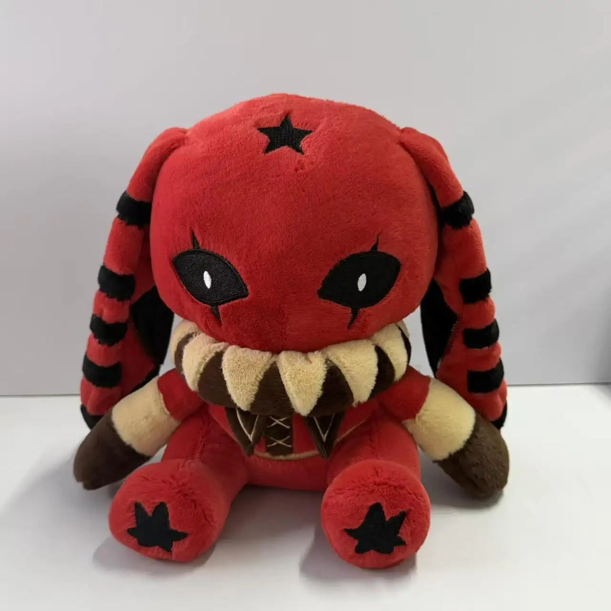 Red and black plush rabbit with star prints, striped long ears, and a ruffled collar.