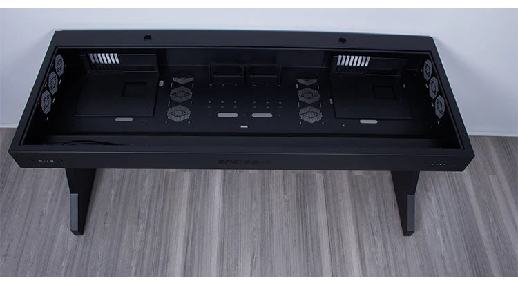 Overhead view of a large black computer desk with a hollow, partitioned chassis integrated into the top.