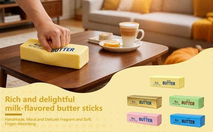 A hand squeezes a yellow stick of butter labeled "4oz. BUTTER" on a wooden coffee table, with four other colored butter sticks shown below.
