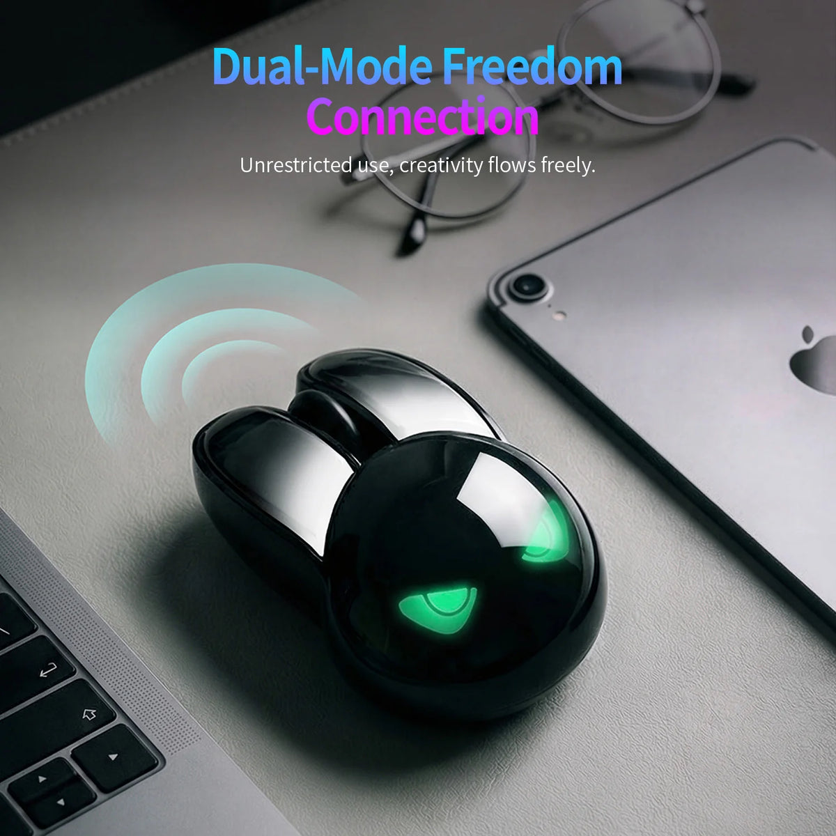 Black rabbit-shaped wireless mouse with glowing green eyes and silver ears on a grey desk.