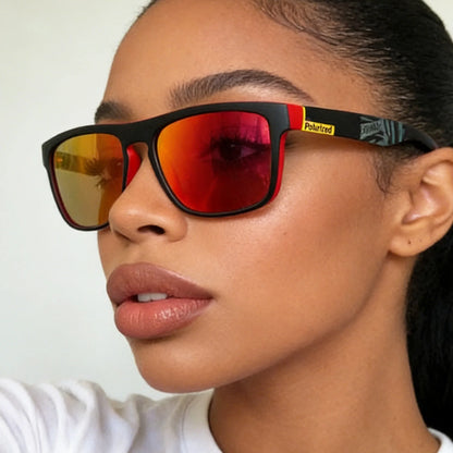 A person wearing black framed sunglasses with red-orange mirrored lenses and yellow polarized branding.
