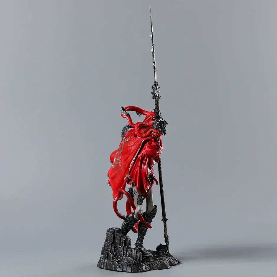 A figurine with a red cloak and horned headpiece, holding a tall spear while standing on a rocky base.