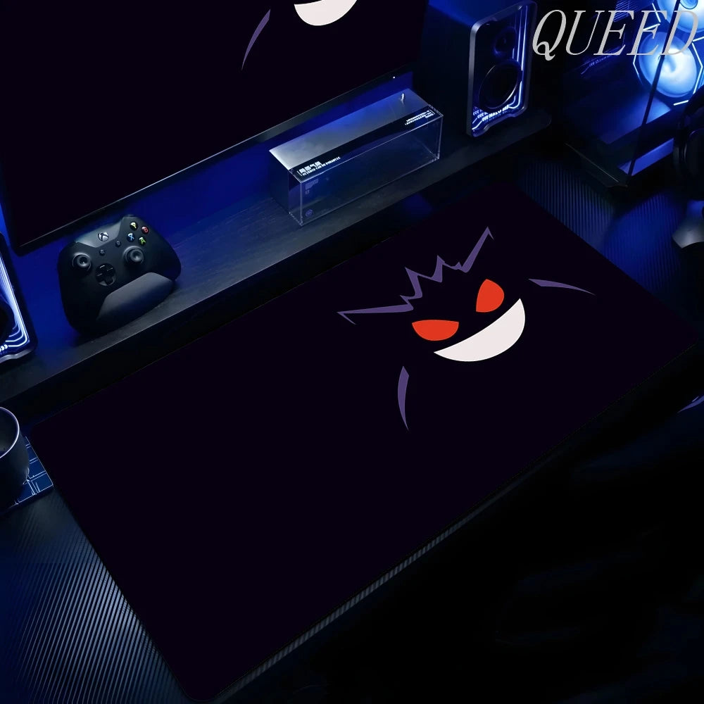 Black XXL gaming mouse pad featuring Gengar's glowing red eyes, white smile, and purple spikes on a desk.