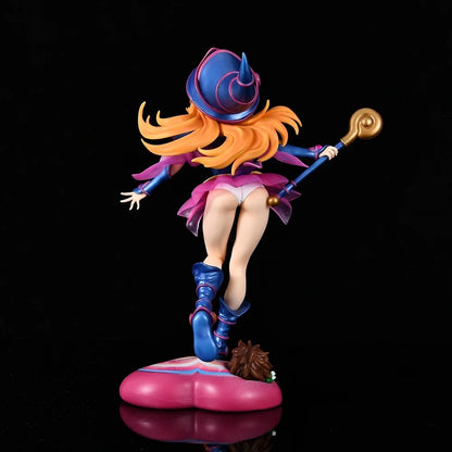Rear view of a blonde anime figurine in a blue hat, pink skirt, and boots, holding a staff, on a pink heart base.