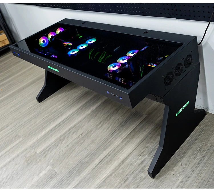 Black computer desk with a glass top housing two integrated PC builds featuring RGB fans.