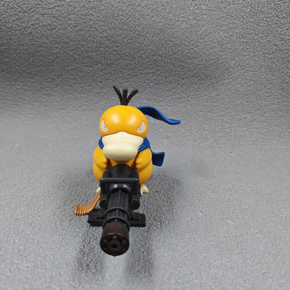 Yellow duck-like figurine with a blue scarf, holding a large black gatling gun, on a grey background.