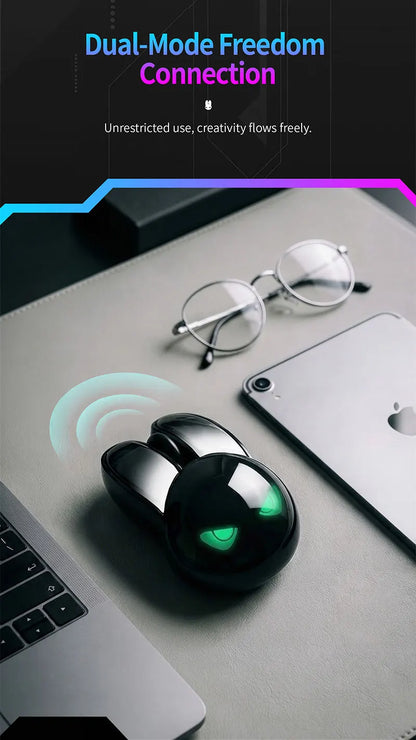 Black MOFII M6C rabbit-shaped wireless mouse with glowing green eyes on a desk with glasses and a tablet.