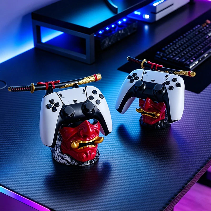 Two red oni mask controller stands with samurai swords holding white and black game controllers on a desk.