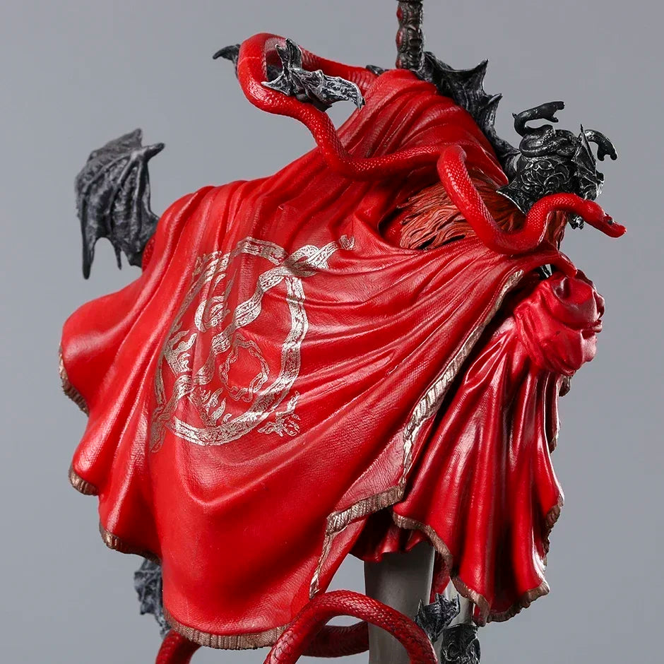 Red-caped figurine with winding red snakes, dark wings, and ornate gold trim seen from behind.