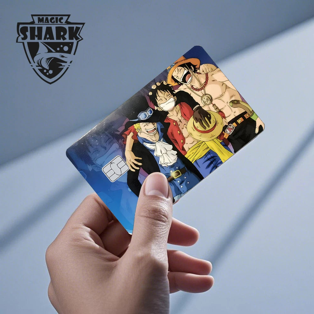 A hand holding a blue credit card skin sticker featuring three smiling anime characters.
