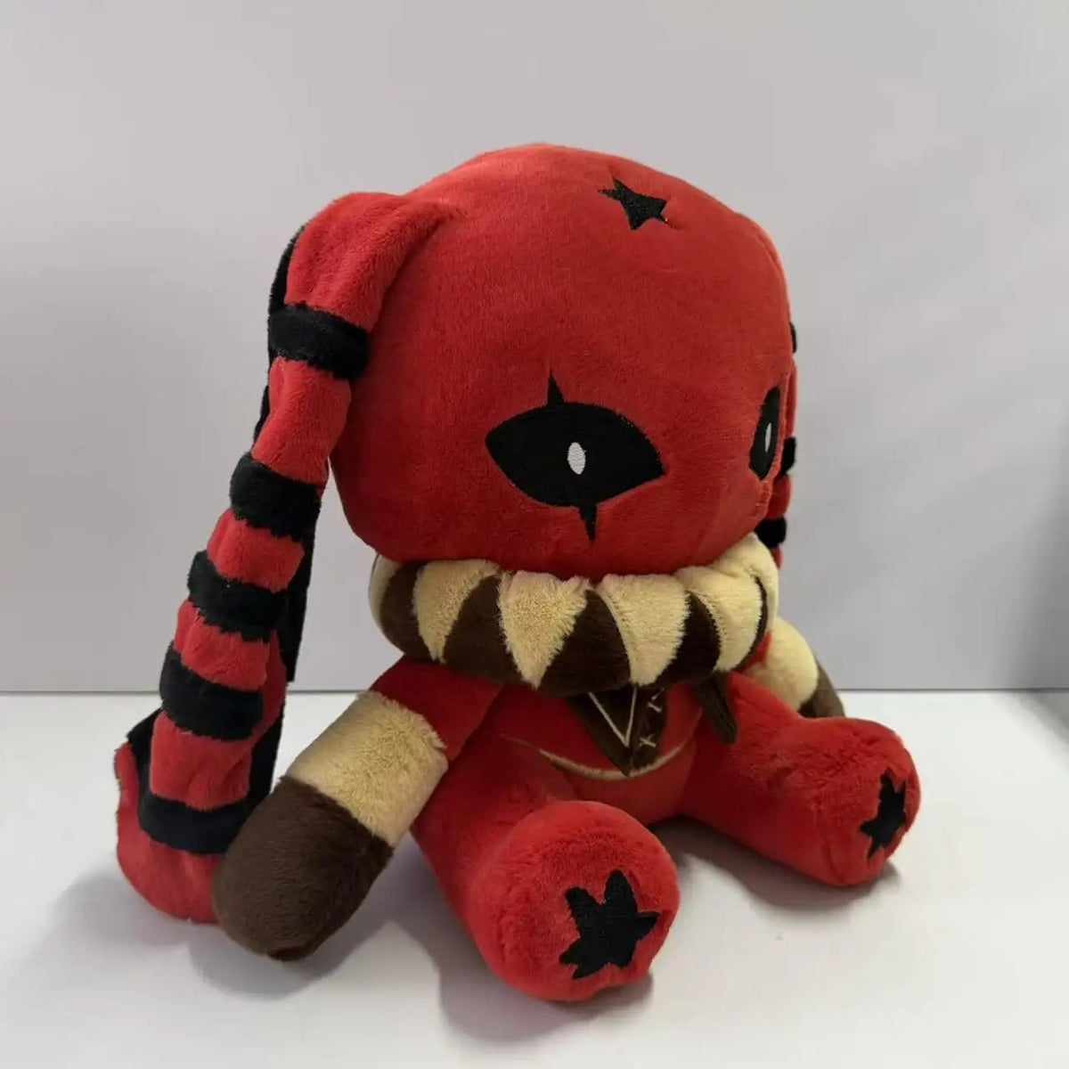 Red and black rabbit plush with long striped ears, star prints, and a ruffled collar.