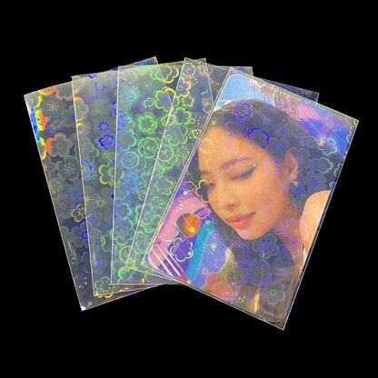 Fan of holographic card sleeves featuring a rainbow flower pattern, with one sleeve containing a portrait.