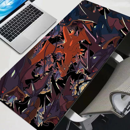 A black XXL gaming desk mat featuring Charizard and Gyarados illustrations, with a laptop nearby.