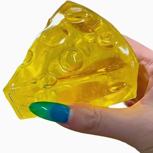 A hand with blue and green nails squeezes a translucent, yellow cheese-wedge fidget toy.