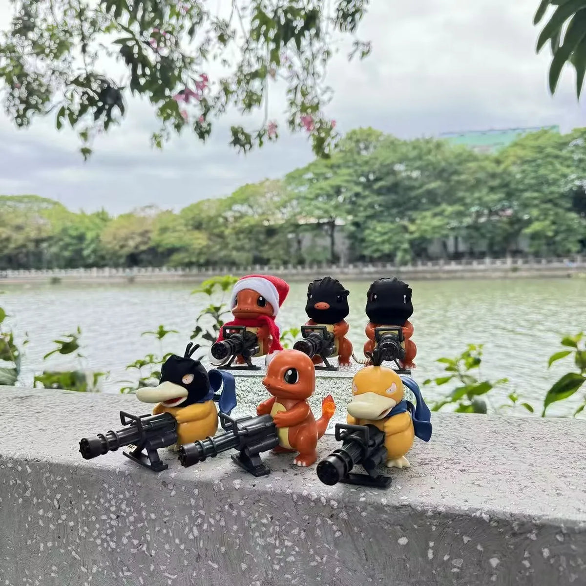 Six orange and yellow Pokémon figurines holding black Gatling guns, displayed outdoors on a ledge.