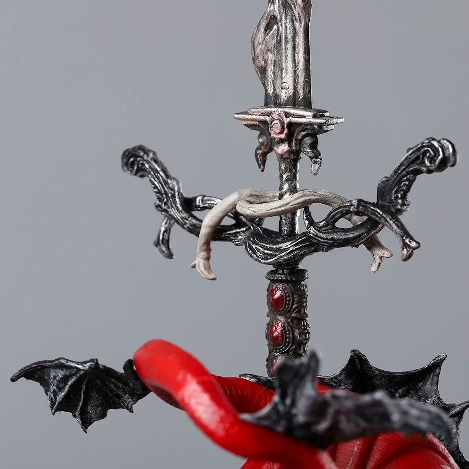 Close-up of a silver sword hilt with intricate dark grey filigree, red jewels, and a wrapped white snake.