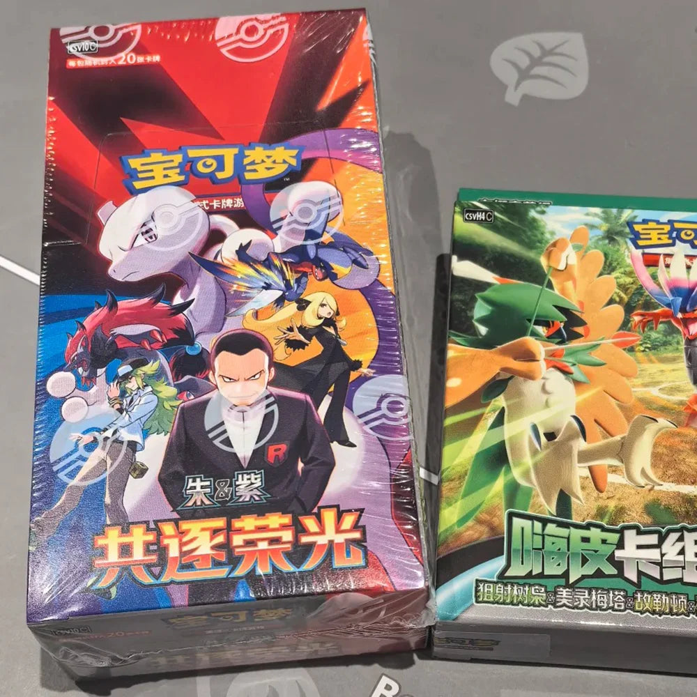 Two Pokémon booster boxes: one red and purple with Mewtwo, and one green with Decidueye.