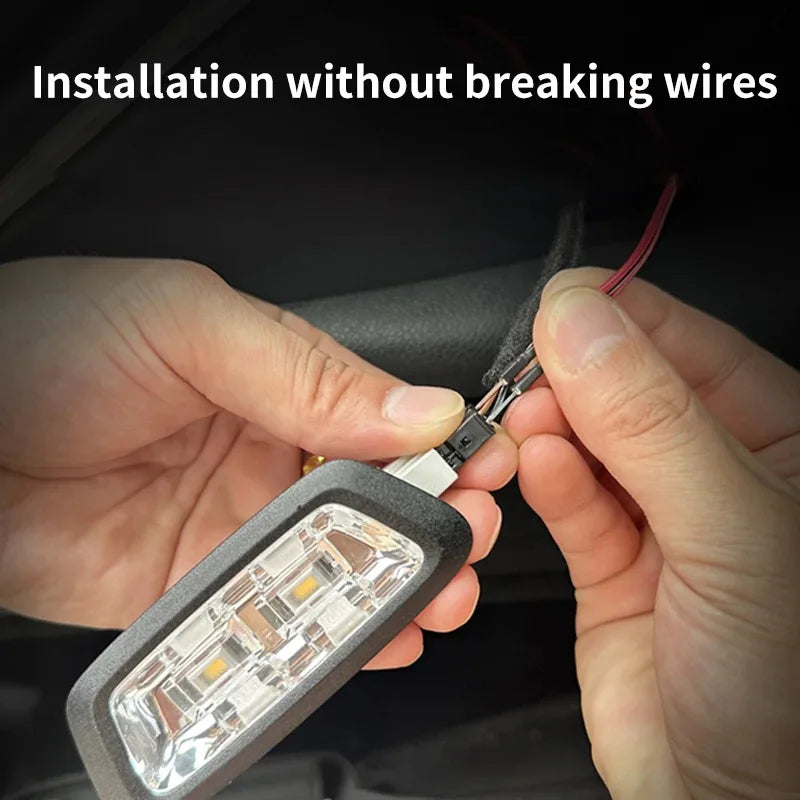 Hands connecting a compact rectangular LED light with a clear lens to vehicle wires.