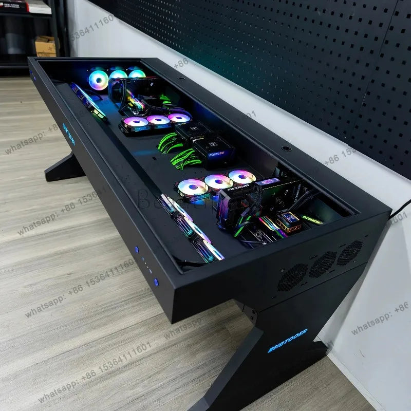 Black desk with an integrated glass-top computer case housing two PC builds with RGB fans and graphics cards.