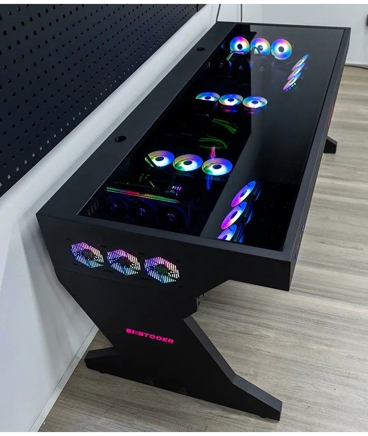 A black desk with a glass top housing PC components and glowing RGB fans. The Z-shaped leg displays the BTOOER logo in pink.