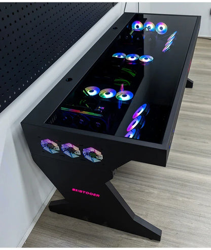 A black desk with a glass top housing PC components and glowing RGB fans. The Z-shaped leg displays the BTOOER logo in pink.