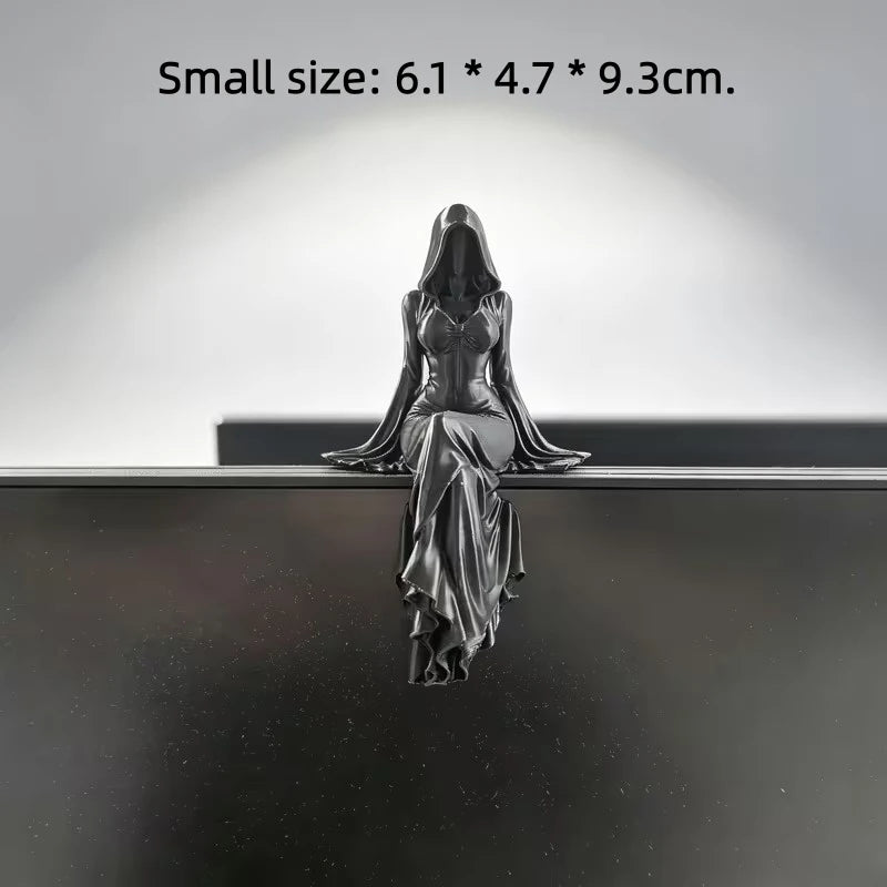Black hooded female figurine sitting with legs dangling, wearing a flowing dress with wide sleeves.