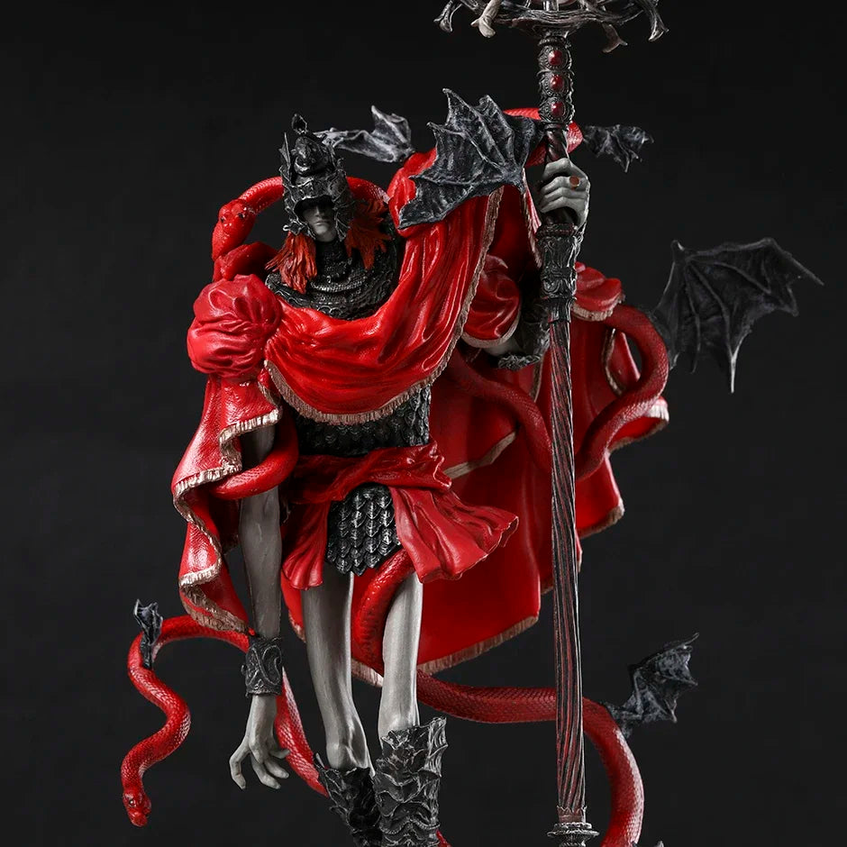 PVC figure of a pale armored warrior with red hair, holding a tall staff, in a bright red cloak with black wings.