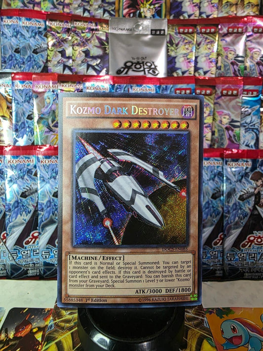 Kozmo Dark Destroyer Secret Rare Yu-Gi-Oh! card against a background of foil booster packs.