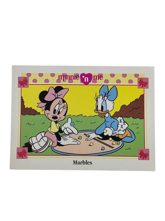 Minnie Mouse and Daisy Duck play marbles outdoors on a yellow and green background.