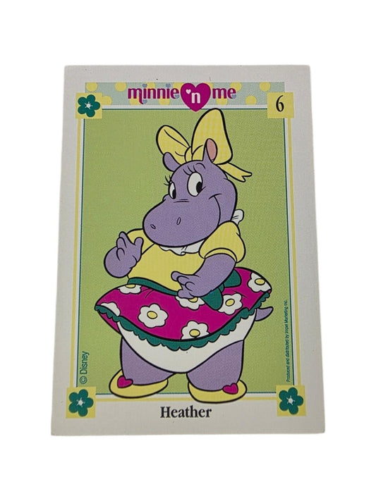 1991 Disney Minnie 'n Me Heather trading card featuring a purple hippo in a yellow bow and skirt, with pink floral skirt.