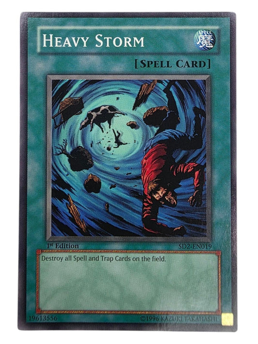 Heavy Storm 1st Edition Yu-Gi-Oh! spell card depicting a blue vortex pulling objects and a person inward.